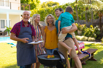 Portrait of cheerful caucasian three generational family barbecuing together in the garden © wavebreak3