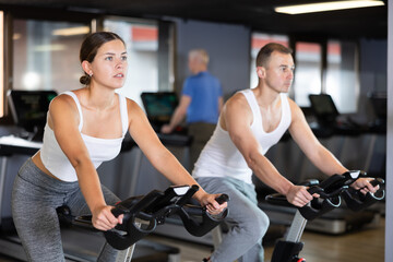 Young athletic woman in sportswear training on exercise bike in gym