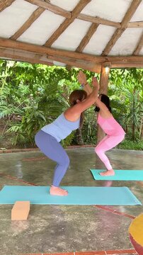 Two Women Practicing Sun Salutation Yoga Flow in Tropical Pavilion