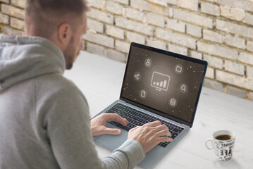 Concept of growth social network marketing industry. Guy work on laptop with conceptual icons.