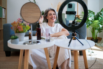 Mature influencer greeting online audience from cozy home living room