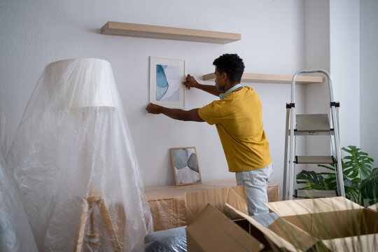 Man decorating living room with framed artwork during move