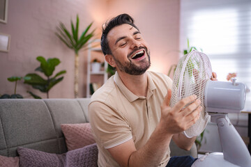 Man refreshing himself with a fan during a heat wave at home
