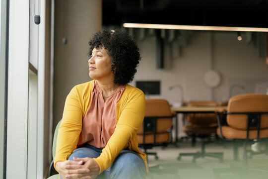 Office worker sitting by a window looking contemplative