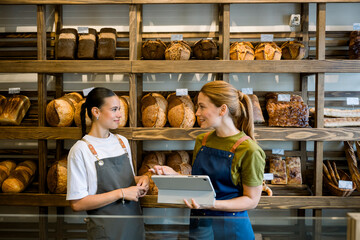 Bakery owner explaining tasks to trainee using digital tablet