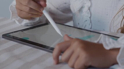 Close up shot from a side angle shows a child using a stylus to interact with a digital tablet interface while drawing. The camera highlights precision, focus and digital learning. High quality 4k - Powered by Adobe