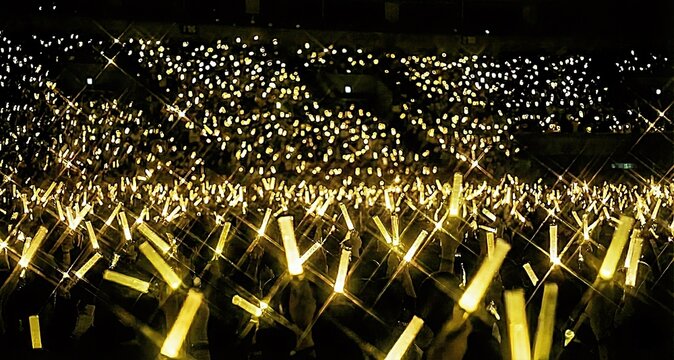 ライブ会場で輝く黄色のペンライトの海　生成AI	