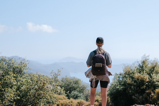 Woman hiking solo with backpack in mountain landscape on sunny day