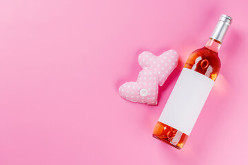 Rose wine and heart toys on pink background