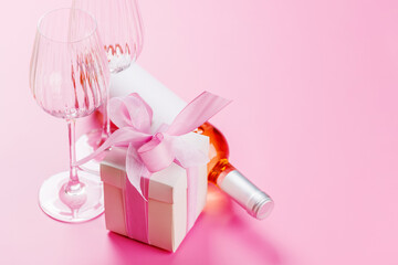 Gift box and wine glasses on pink background