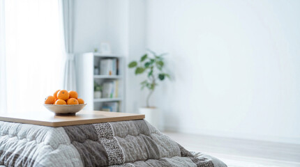 白いカーテンの前に置かれたモダンなこたつとみかん