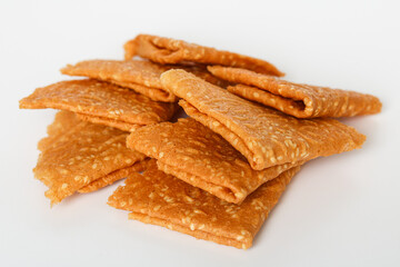 Closeup of crispy, golden-brown Kue Semprong or Love Letter cookies, a thin, folded Southeast Asian snack. Isolated on a white background.