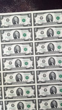 Rows of Thomas Jefferson portraits on uncut two dollar bills. Full frame background of an uncut sheet of US 2 dollar banknotes.