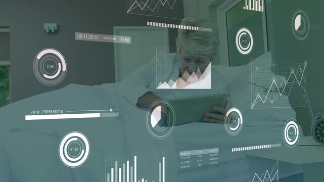 Senior woman reclining on bed, viewing financial data charts floating around tablet screen