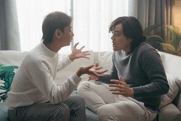 Asian gay couple having Serious emotional talk ,heated discussion in living room at home