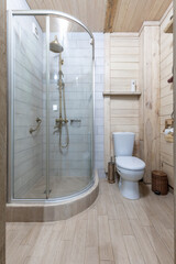 Bright rustic bathroom interior with glass shower and wooden walls