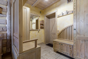 Rustic entryway interior with handcrafted wooden furniture and yellow walls
