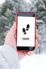 Hand holding smartphone displaying 10000 steps fitness goal