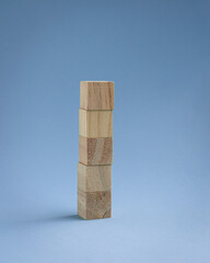 Five blank square wood blocks stacked up, isolated on light blue background.