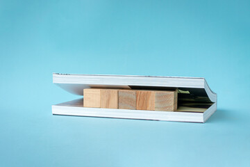 Five square wooden blocks in between pages of a book.