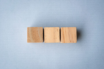 Three blank wooden square blocks in a row