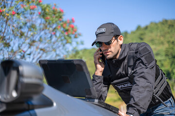 The police officer is working with rugged laptop at the dam.