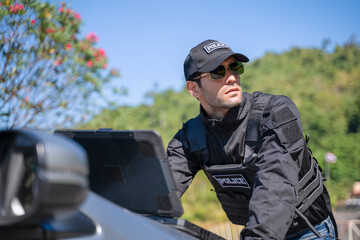 The police officer is working with rugged laptop at the dam.