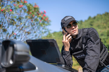 The police officer is working with rugged laptop at the dam.
