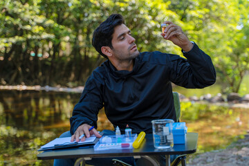 The environmentalist is testing a water Stream in the forest.
