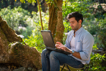 White collar worker is using ragged laptop while vacation at forest.