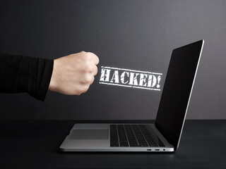 Fist hitting laptop with hacked message appearing on screen