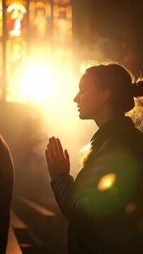 Person devoutly praying, hands together in worship. Golden light illuminates the sacred space through vibrant stained glass, evoking deep spiritual reverence and contemplation.