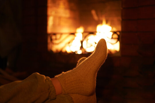 Cozy scene featuring a pair of warm, knitted socks resting comfortably in front of a glowing fireplace, creating a serene atmosphere for relaxation and comfort