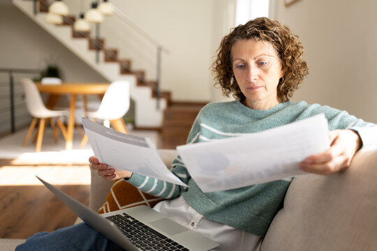 Woman managing home finances, reading bills and documents