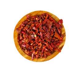 Dried red chili flakes in wooden bowl top view