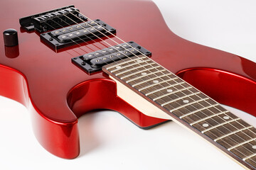 Close up of red electric guitar with dark fretboard and humbucker pickups