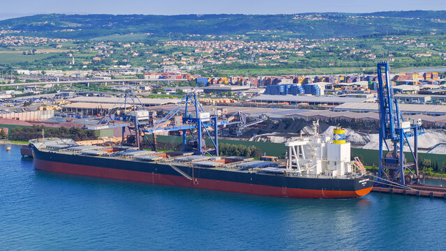 AERIAL: Container cranes hover above a large freight ship docked in Luka Koper.