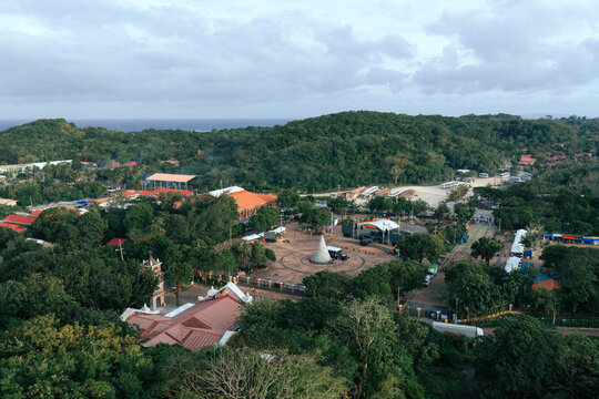 Aerial view of the white monument encircled by a dark brick path and lush trees, contrasted against the orange roofs of the buildings, Caluya, Western Visayas, Philippines.