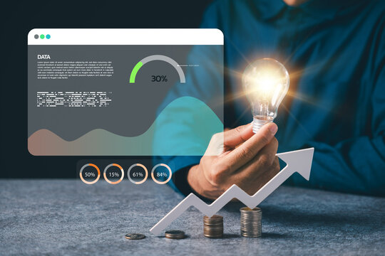 Hand holding glowing lightbulb bulb shows business idea growth concept, marketing solution success depends on creative thinking plus financial data analysis using charts and coins - Powered by Adobe