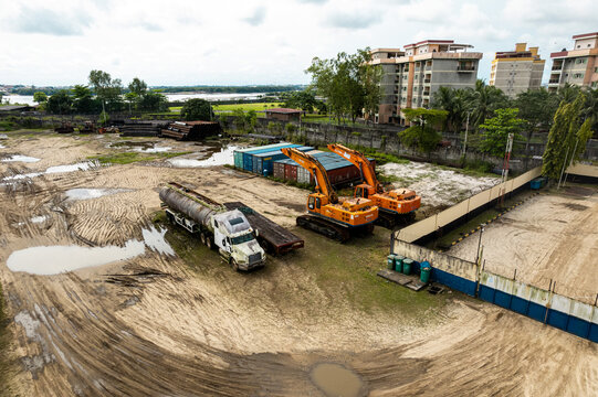 Aerial view of construction equipment and a tanker truck resting on a sandy lot near buildings and greenery, Opobo, Rivers State, Nigeria.