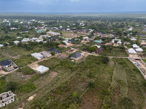 Aerial view of scattered houses and buildings nestled within lush greenery under a cloudy sky, creating a harmonious blend of nature and architecture, Egbema, Rivers, Nigeria.