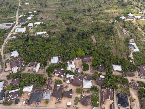 Aerial view of thatched and corrugated roofs nestle amidst verdant trees, creating a mosaic of textures and tones, Obor Road, Egbema, Rivers, Nigeria.