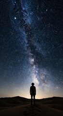 Solitary figure observes the brilliant celestial band stretching across the dark desert night sky