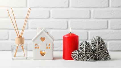 Cozy home decor with candle and heart shaped ornaments on white shelf