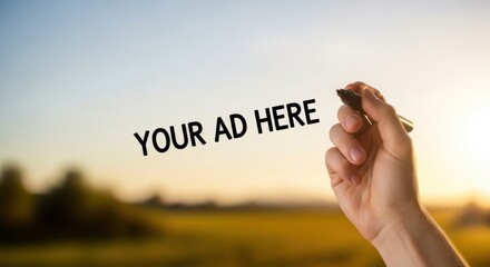 Hand holding marker with YOUR AD HERE text in sunset field