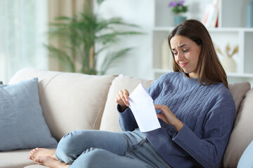 Doubtful woman putting letter in envelope