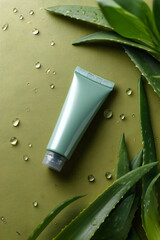 Green tube of cream placed on a leaf surface surrounded by droplets of water