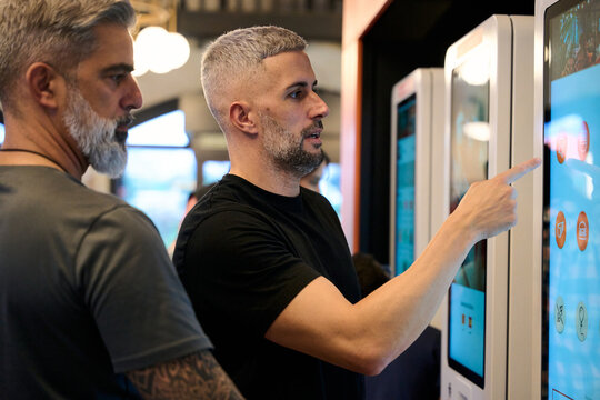 Men ordering fast food using self service kiosk
