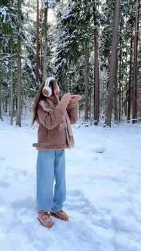 Teenage girl dancing freely in a snowy forest, enjoying nature and winter atmosphere. Joyful outdoor activity, freedom, mindfulness and connection with nature.