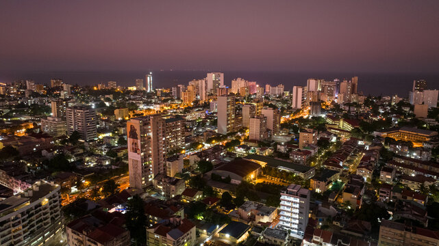 Aerial view of the city lights twinkle against the darkening sky, illuminating the skyline and coastal horizon, Maputo, Cidade de Maputo, Mozambique.
